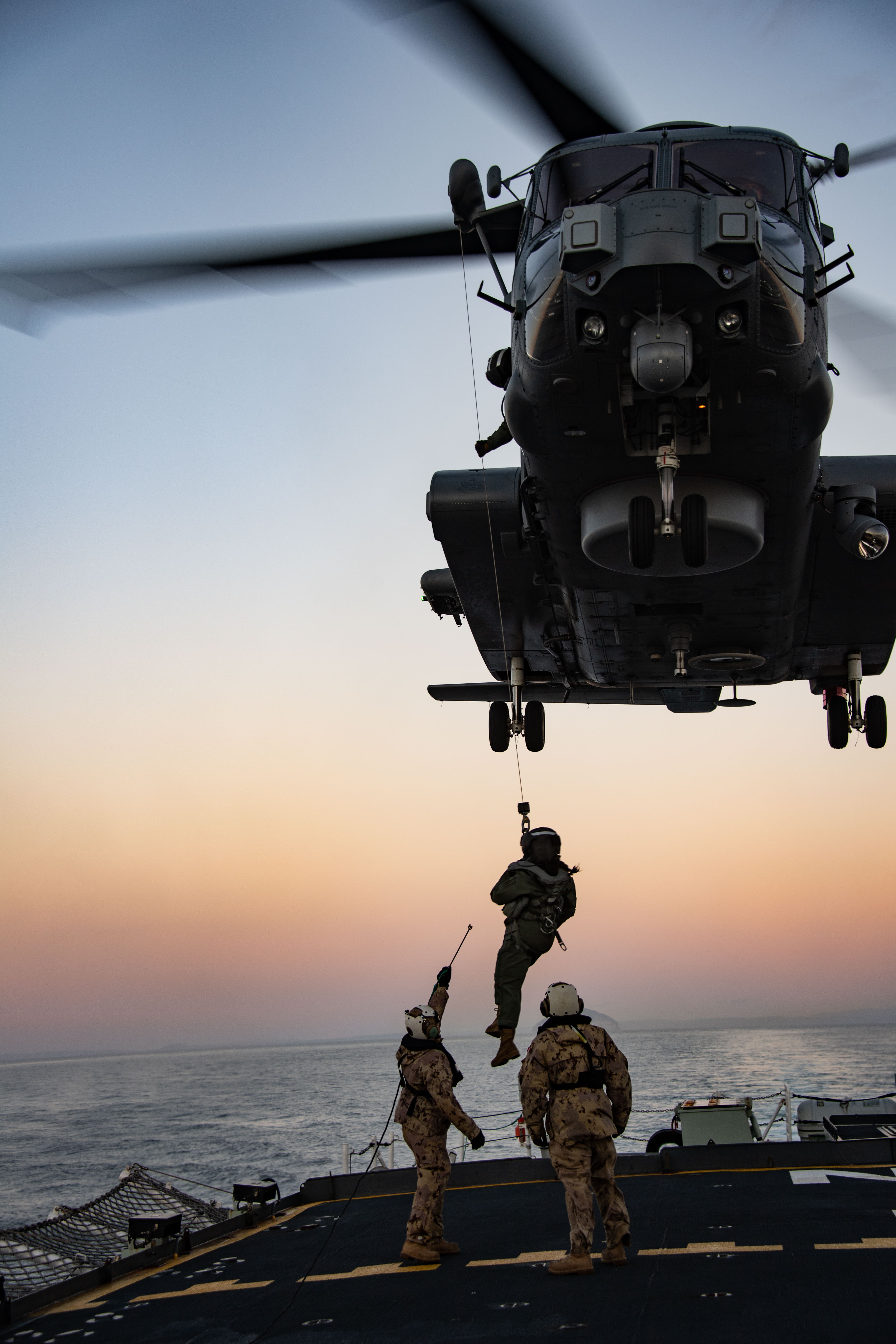 Corporal (Cpl) Mathieu Roy and Cpl Theodore Ardelian assist Captain Catherine Drover disembark from a CH-148 Cyclone helicopter during a hoisting exercise aboard HMCS Fredericton, which took place off the coast of Scotland during Operation Reassurance, September 19, 2021.