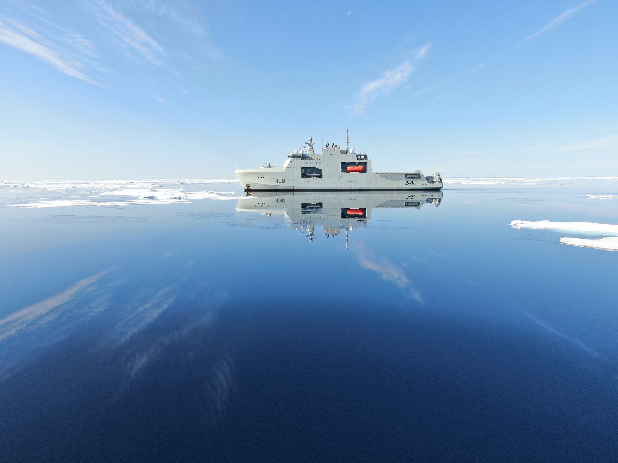 La silhouette du NCSM Harry DeWolf se reflète sur l’eau glacée de l’Arctique. Le NCSM Harry DeWolf a navigué dans l’Arctique plus tôt cette année dans le cadre de sa tournée de six mois de l’Amérique du Nord.